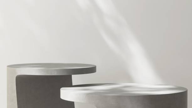 istock Two gray geometric shape concrete cement table in dappled sunlight on white wall 2163554834