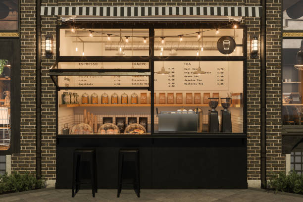 Front View Of Take-Away Coffee Shop With Black Stools At Night