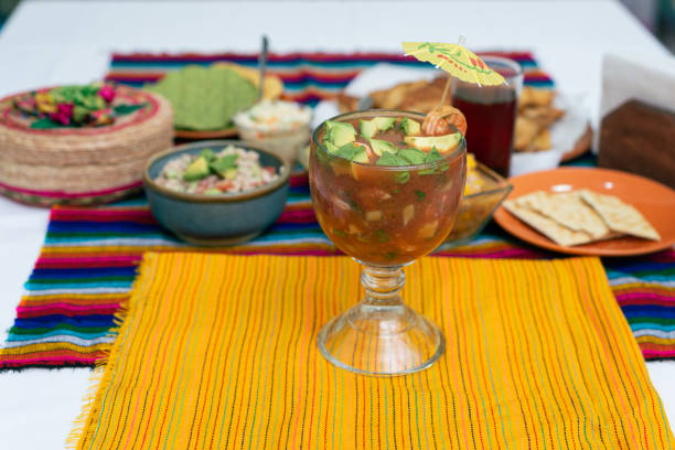 istock Shrimp cocktail with avocado cubes in a chabela glass and other fish-based dishes on a colorful tablecloth. 2163558314