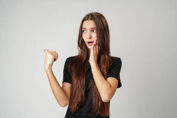 istock Young Woman Pointing to Copy Space Against a Light Background 2163558369