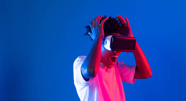 istock Surprised African looking VR holding object hologram neon wall. Contrivance. 2163565949