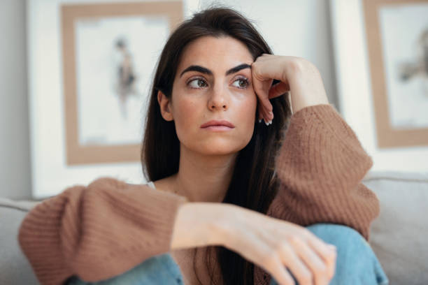 istock Depressed young woman overthinking while sitting on the couch at home 2163567436