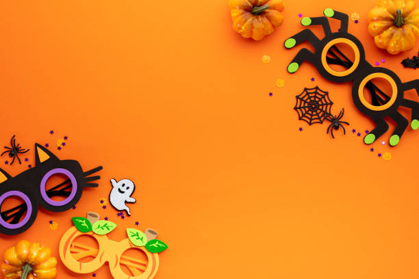istock Festive Halloween decor on vibrant orange backdrop perfect for holiday-themed projects, invitations, and marketing materials. Includes pumpkins, ghost, spider webs, and confetti. 2163568013