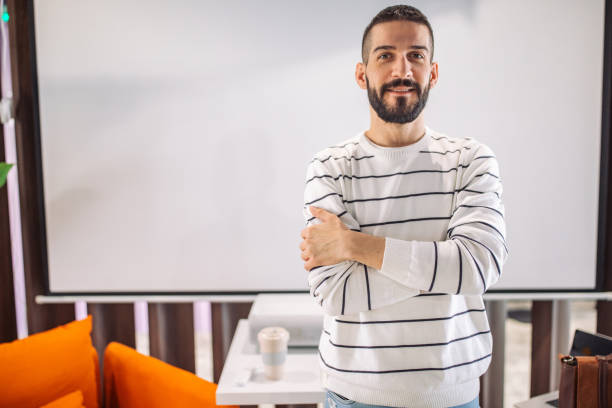 istock Man in striped sweater crossing arms in modern office. 2163570573