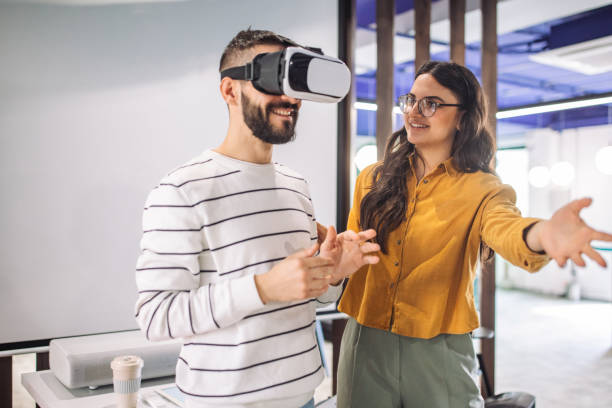 istock Man wearing VR headset, guided by colleague in meeting 2163571478
