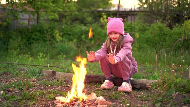 istock A girl near a small campfire in nature. 2163573400