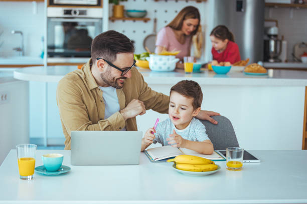 Caucasian Father and Young Son Engaging with Technology in Dining Room