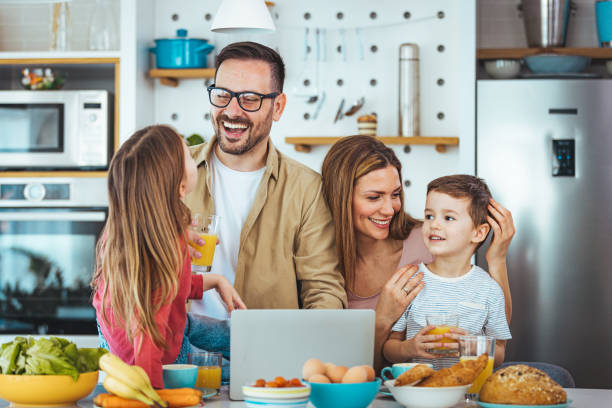 istock Smiling Family Using Laptop During Breakfast in Modern Kitchen 2163573860