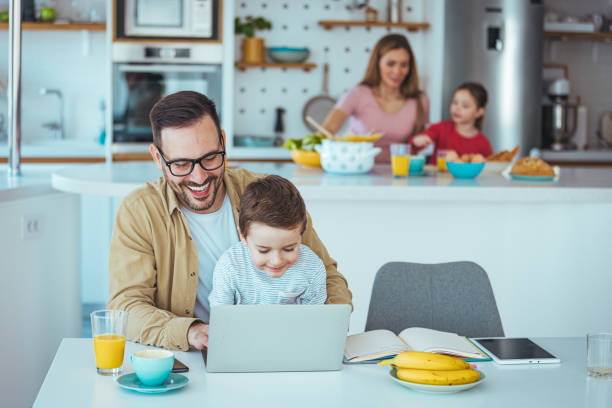 istock Joyful Father and Young Son Engaging with Laptop in Kitchen 2163573885