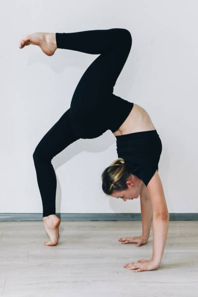 istock Flexible, slender girl gymnast in a bridge pose on a white background. 2163573899