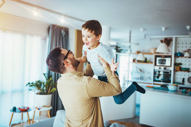 istock Joyful Caucasian Father Lifting Young Son Indoors 2163573904