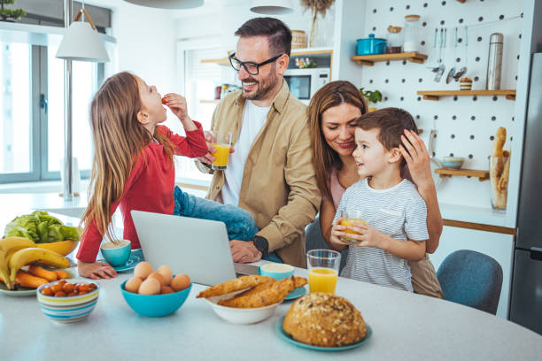 istock Caucasian Family Enjoying Breakfast and Web Browsing in Kitchen 2163573913