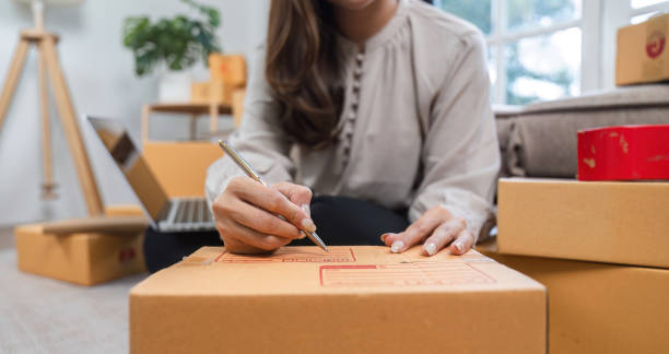 istock Young Woman Preparing Packages for Online Sales at Home, Writing Labels on Boxes, E-commerce Business Concept 2163576342