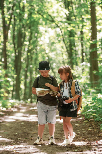 istock Checking the way on the map. Kids in forest at summer daytime together 2163576355
