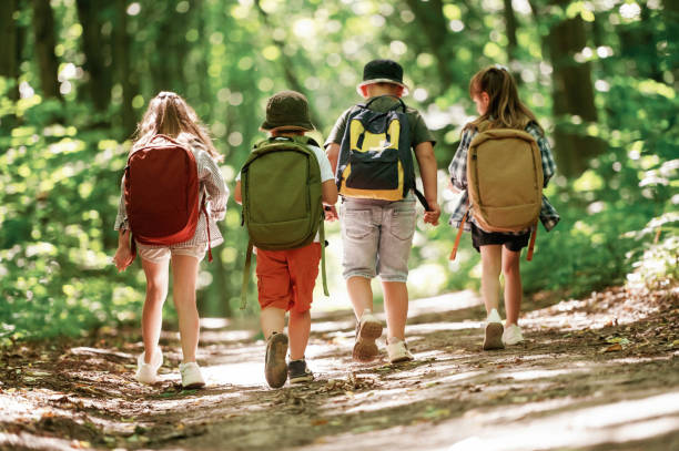 istock With backpacks. Kids in forest at summer daytime together 2163576487