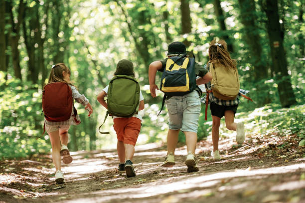 istock With backpacks. Kids in forest at summer daytime together 2163576496