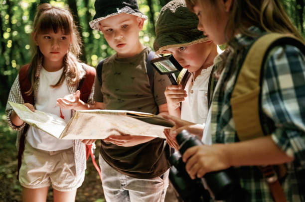 istock Looking at the map. Kids in forest at summer daytime together 2163576682