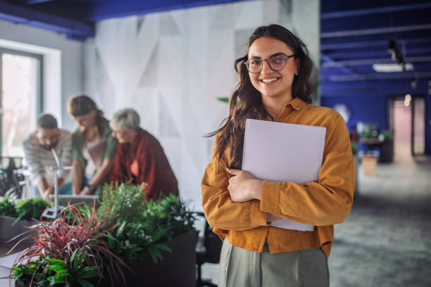 Smiling professional woman standing with a folder.