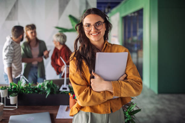istock Smiling woman holding documents in an office setting. 2163577086