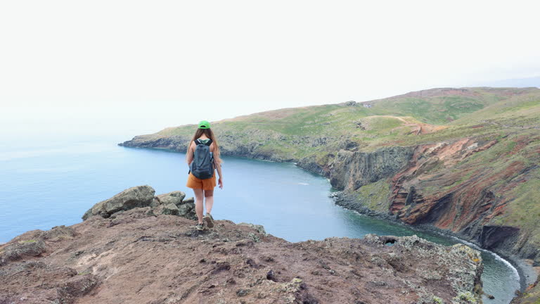 Female Traveller Hiking at Majestic Rocky Coastline Admiring Ocean Views on Madeira Island