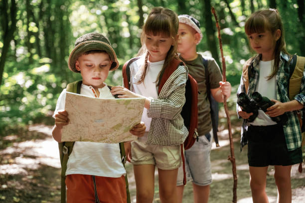 istock Smart boy is reading the map. Kids in forest at summer daytime together 2163581735