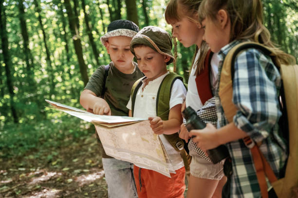 istock Smart boy is reading the map. Kids in forest at summer daytime together 2163581745
