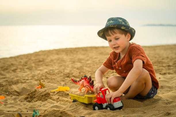 istock Cute boy playing with sand on the beach 2163581952