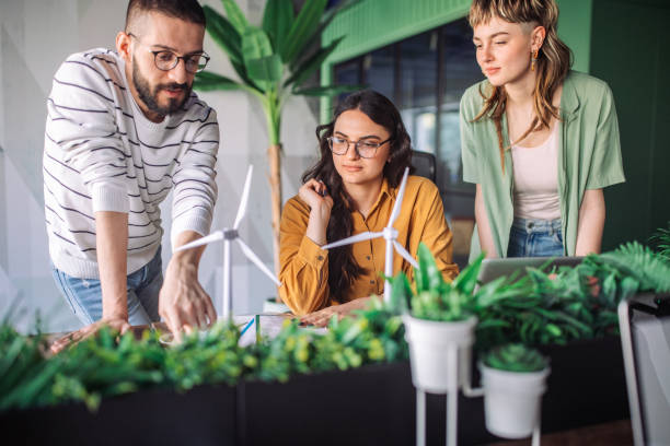 istock Teams analyzing wind turbine models with plants on desk. 2163582140