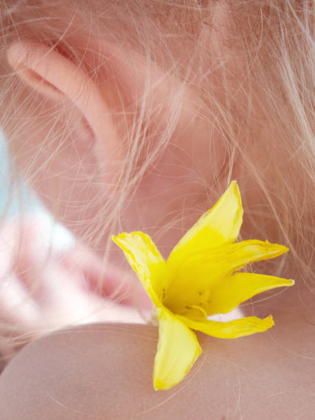 Little girl among dahlia flowers against a green background. Concept: childhood, curiosity, connection with nature; warm family mood.