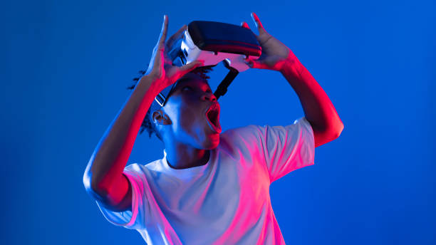 istock Surprised African looking VR holding object hologram neon wall. Contrivance. 2163583432