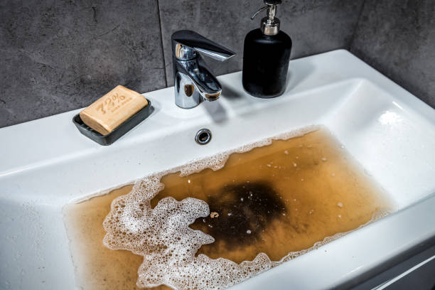 istock Clogged sink in bathroom, sink with dirty water, brown soap. Plumbing problems 2163584653