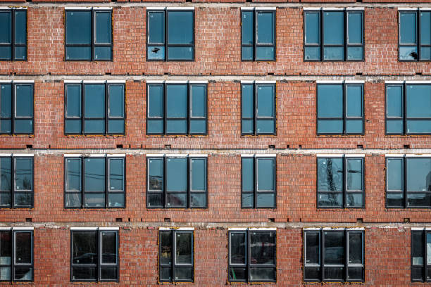 Brick wall of modern skyscraper building under construction, installed windows as a texture