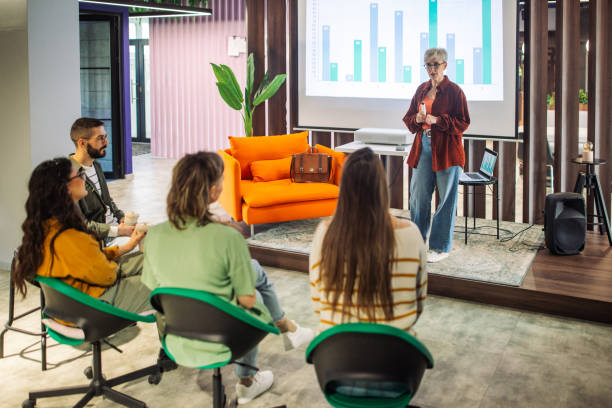 istock Woman presenting charts to small group in modern office. 2163586218