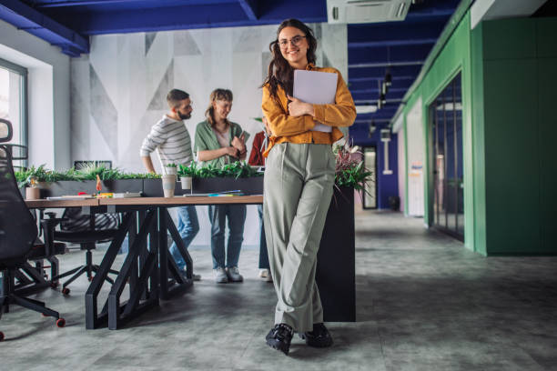 Woman standing by desk in open office environment