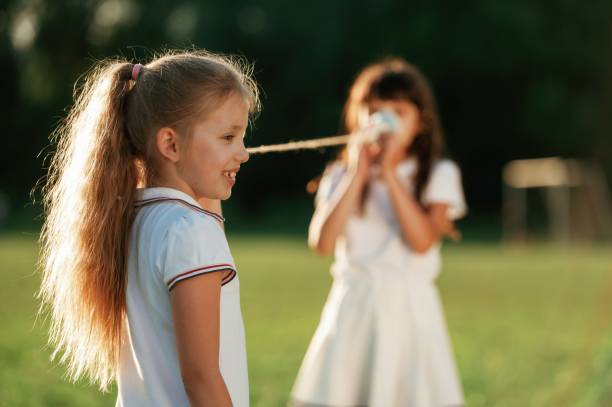 istock Using tin can telephone. Happy kids are on the summer field 2163589802