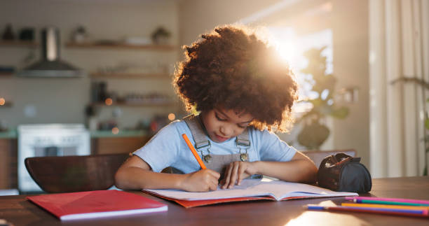 istock Boy, home and writing homework on table in house, education and school work with kid or notebook. Child development, growth and studying for test or exam, apartment and academic knowledge with pen 2163595588