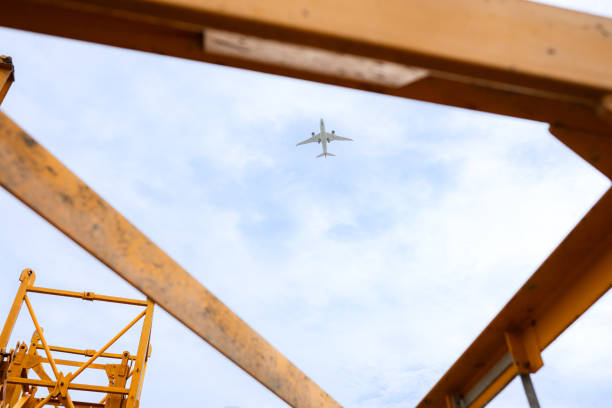 Tower crane in at construction site with air plane on sky in the background