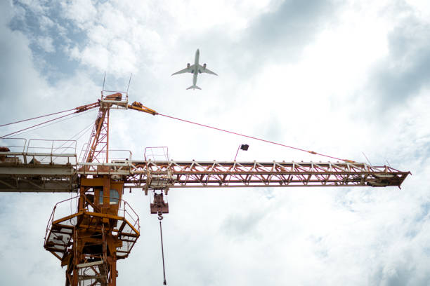 Tower crane in at construction site with air plane on sky in the background