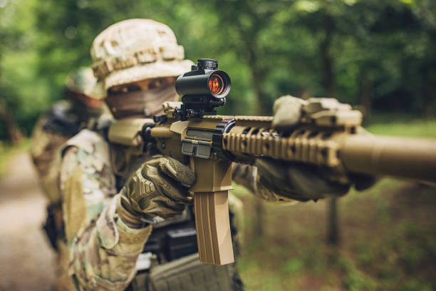 istock Soldier aiming rifle in forest with tactical gear on. 2163599226
