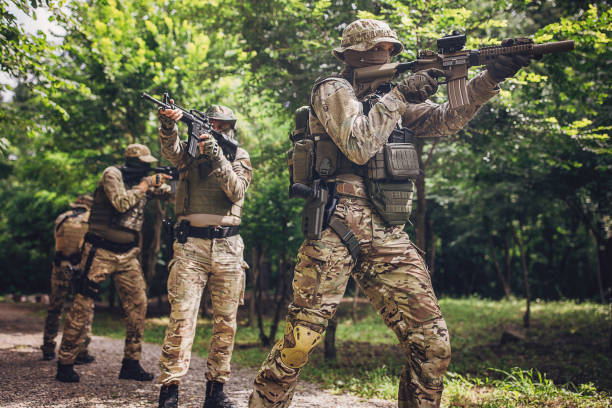 istock Squad of soldiers aiming rifles in forested terrain. 2163599324
