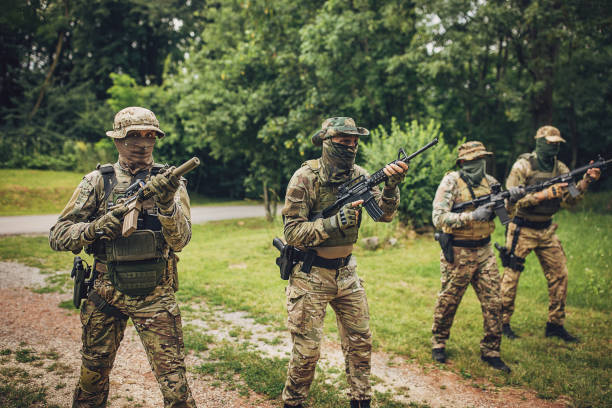 istock Soldiers in tactical gear aiming rifles on grassy terrain. 2163599475