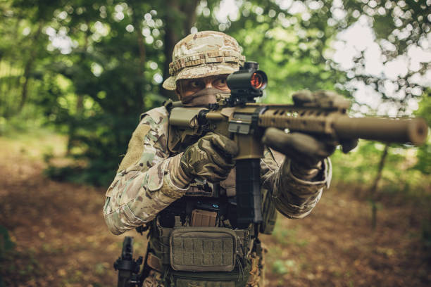 istock Soldier with rifle aiming in forest environment. 2163600991