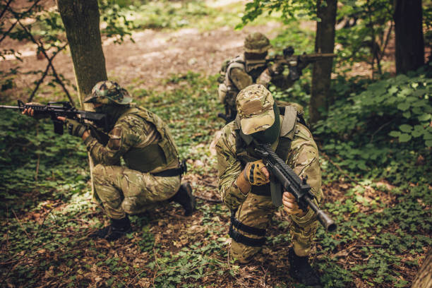 istock Camouflaged soldiers aiming and navigating the woods. 2163602979