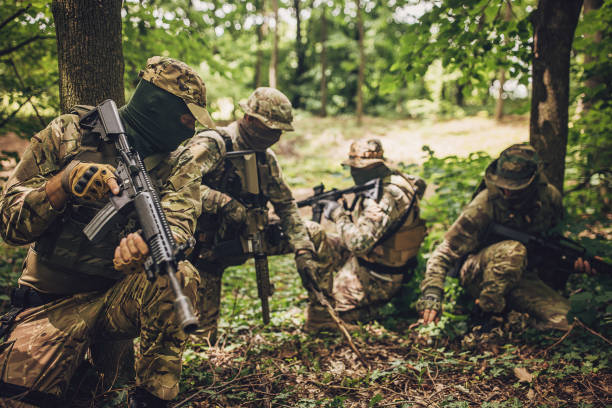 istock Four soldiers in tactical gear in a forest setting. 2163603353