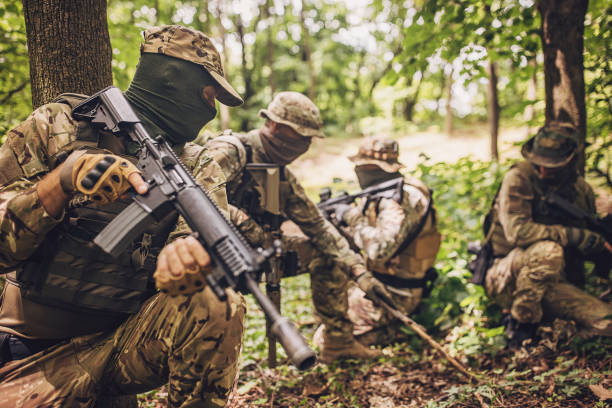 istock Four armed soldiers in tactical gear in the forest. 2163603475