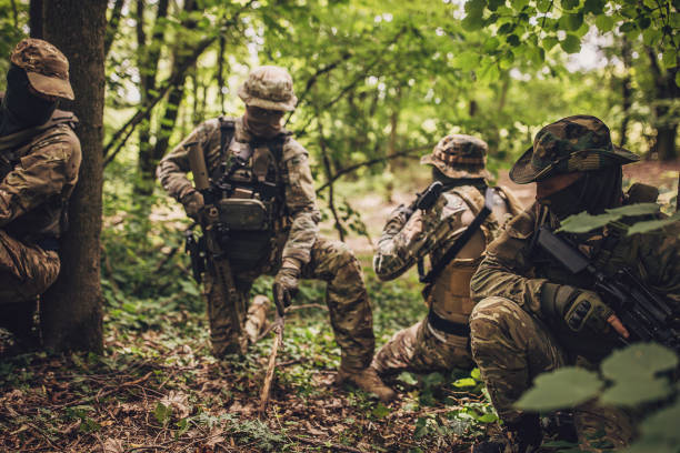 istock Soldiers with camouflage and rifles in forest area. 2163603668