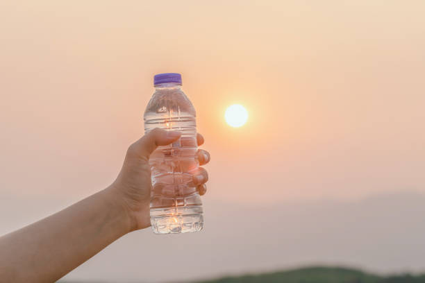 istock Hand holding water bottle on sunset background 2163605814