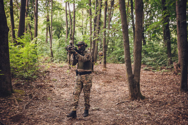 istock Masked soldier aims weapon in dense forest patrol 2163606494