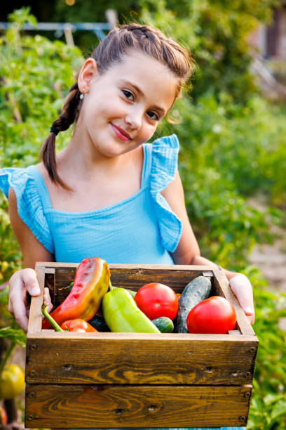 Smiling girl posing for camera while showing basket full of fresh vegetables