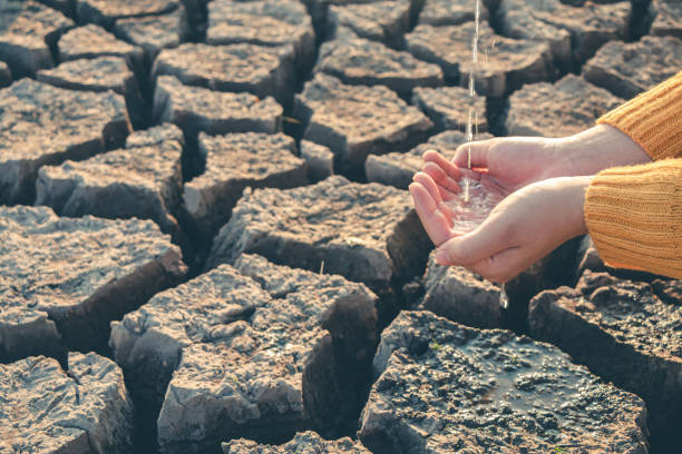 istock Water droplets in hand on barren ground. 2163609585
